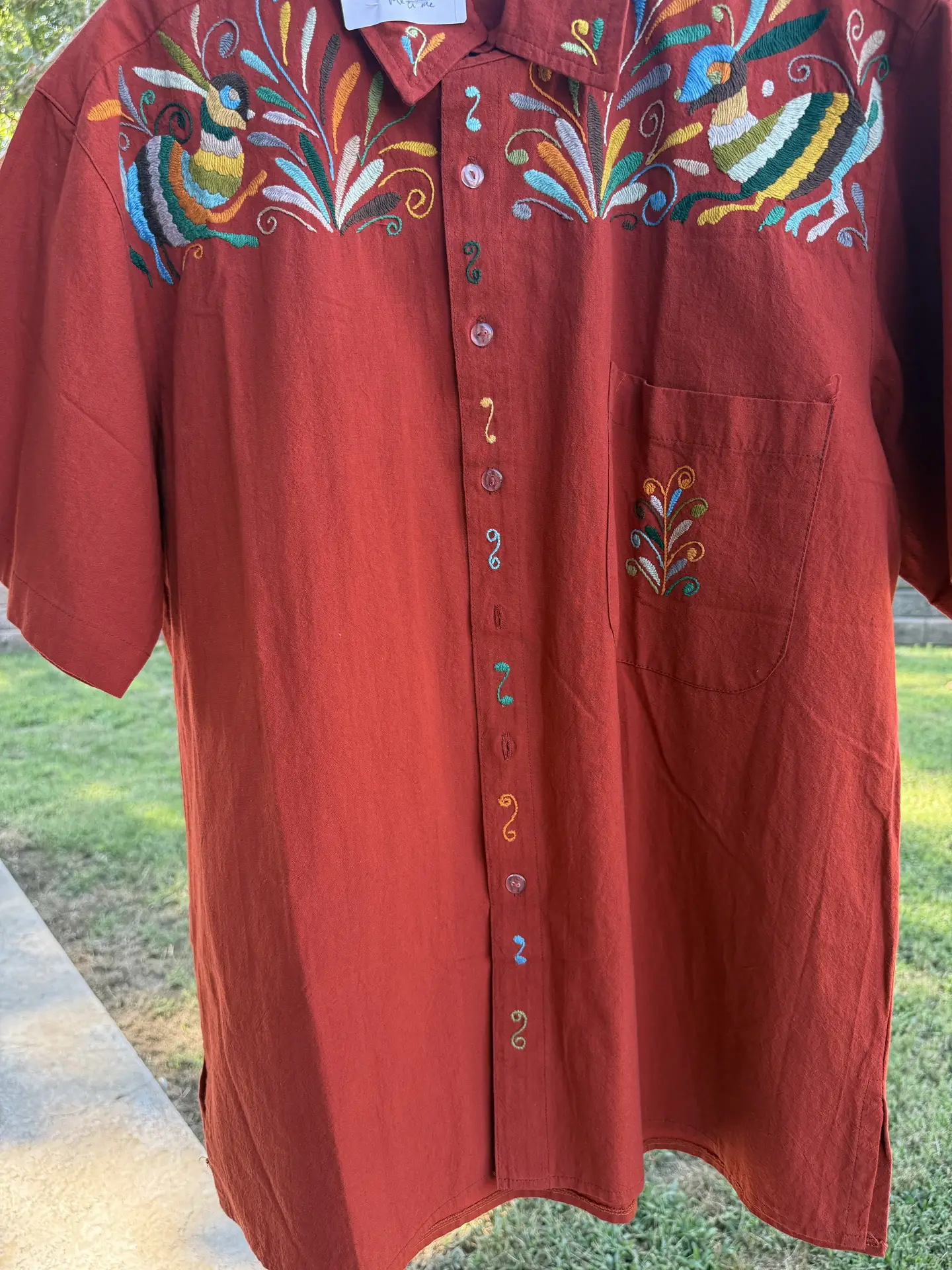 Front view of the brick colored short-sleeve shirt featuring upper multi-color embroidery.