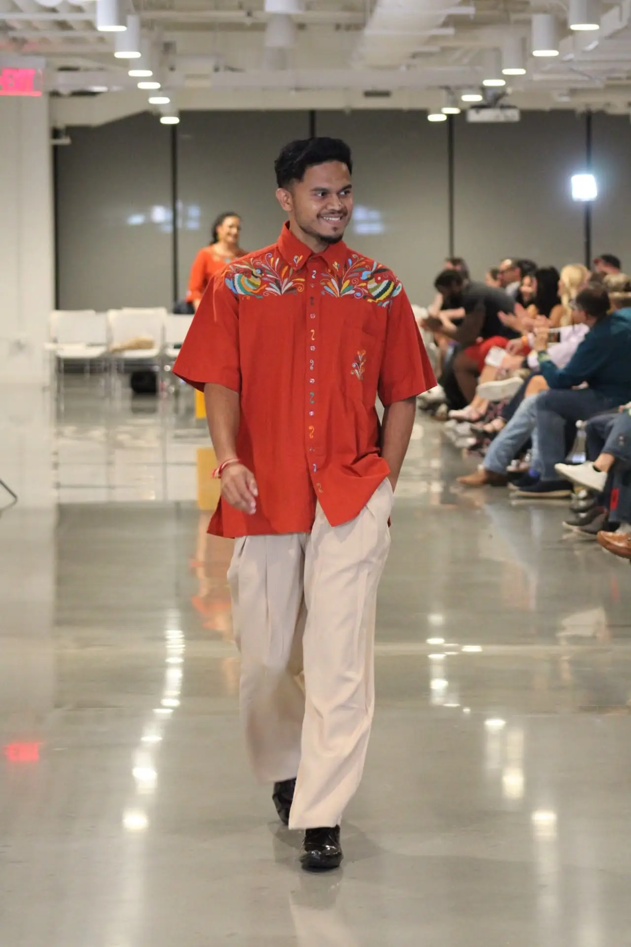 Man wearing a brick colored short-sleeve shirt with vibrant Tenango embroidery.