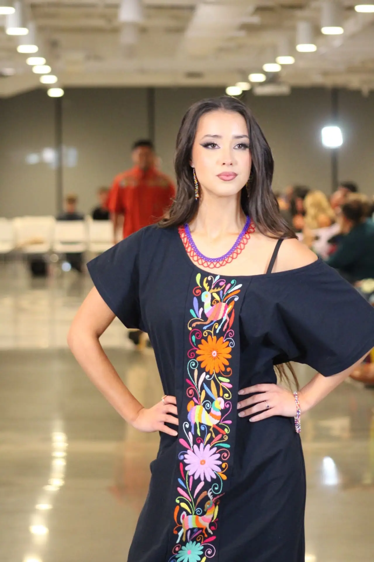 Woman wearing a navy blue Tenango dress with multi-color embroidery.