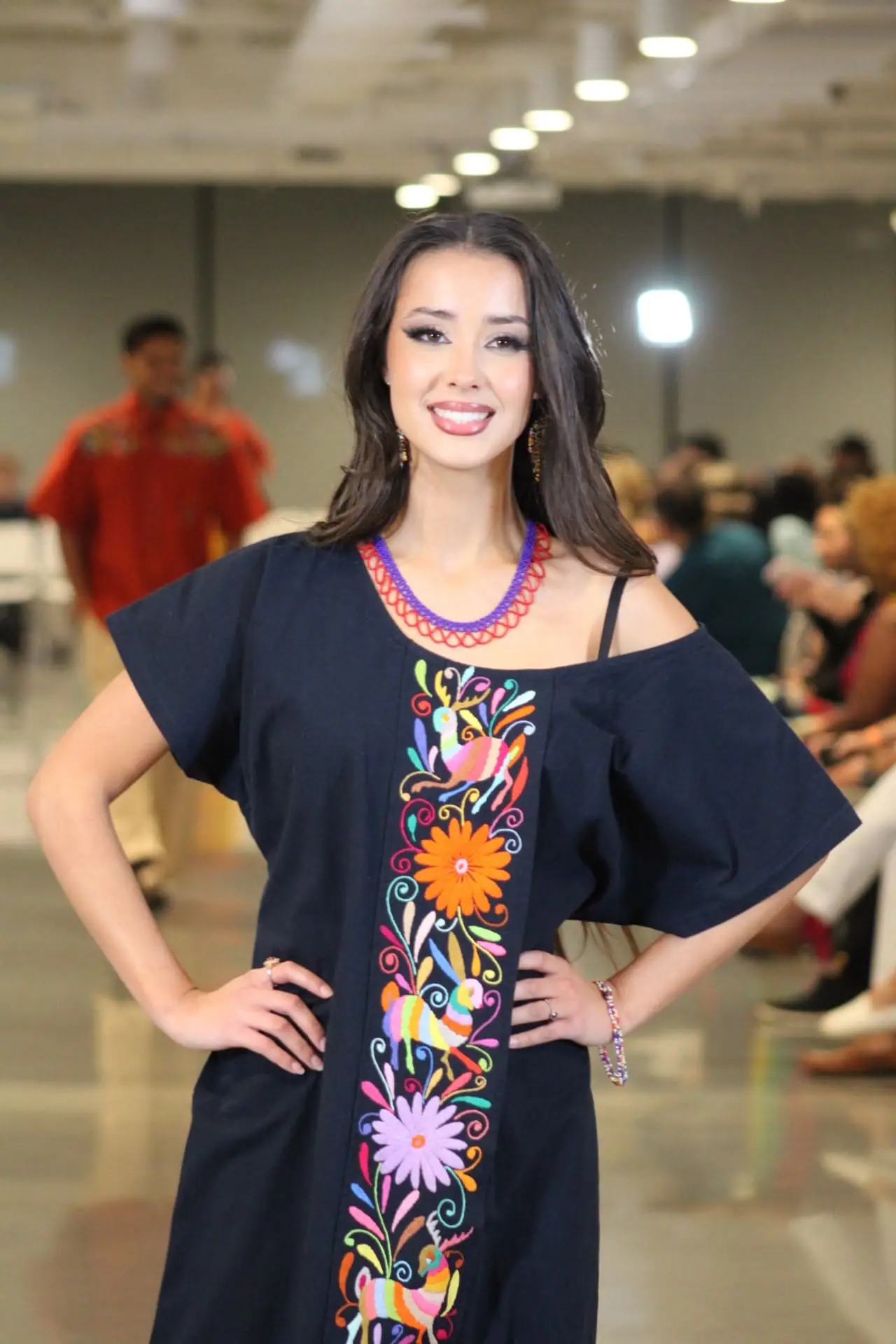 Woman wearing a navy blue Tenango dress with a vibrant central floral embroidery panel.