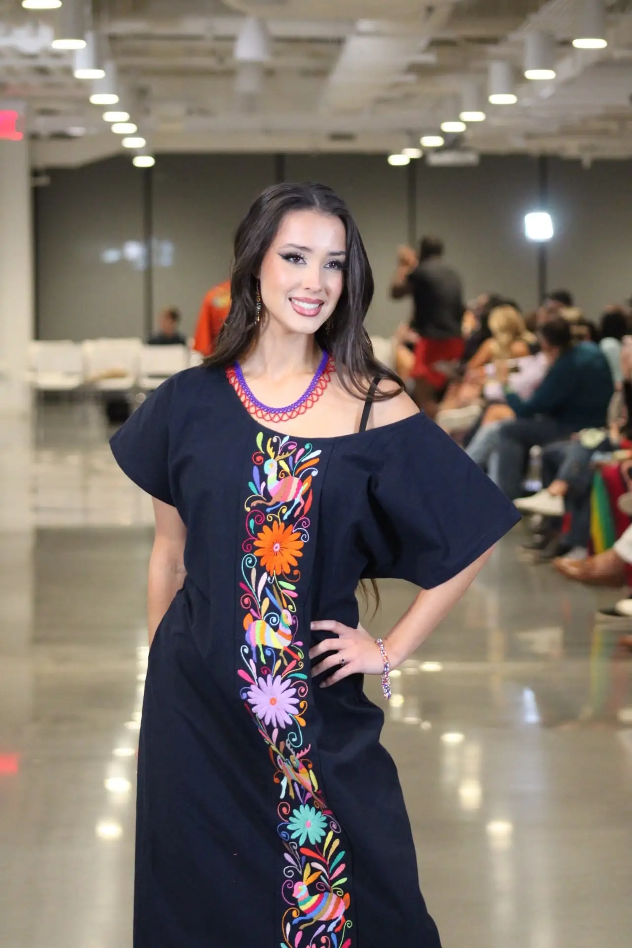 Woman wearing a navy blue Tenango dress with a vibrant central embroidered panel.